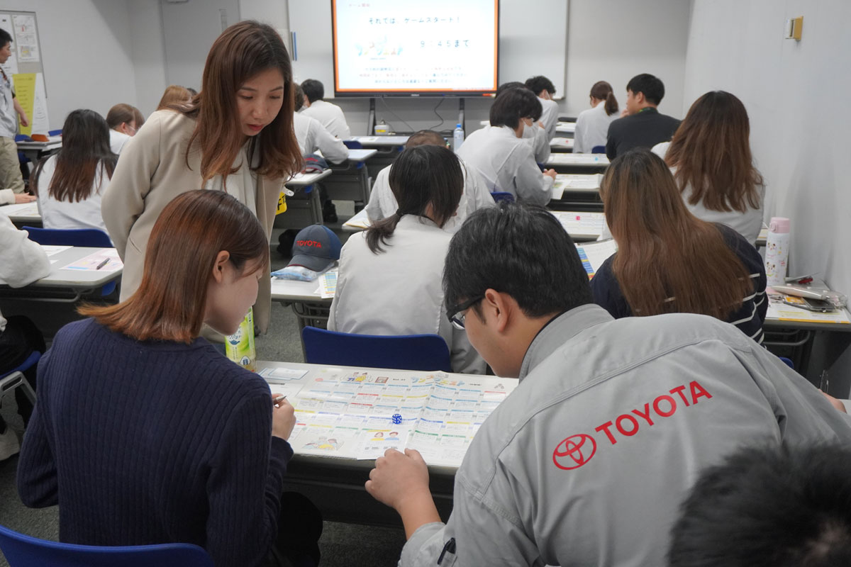 産前・産後・育児を疑似体験するすごろくに取り組むトヨタ自動車社員ら。奥は講座を担当したmanma講師